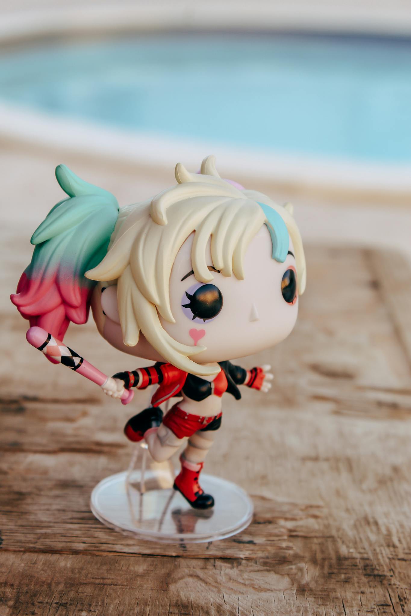 A vibrant, collectible cartoon figure by the poolside on a wooden surface, perfect for toy enthusiasts.